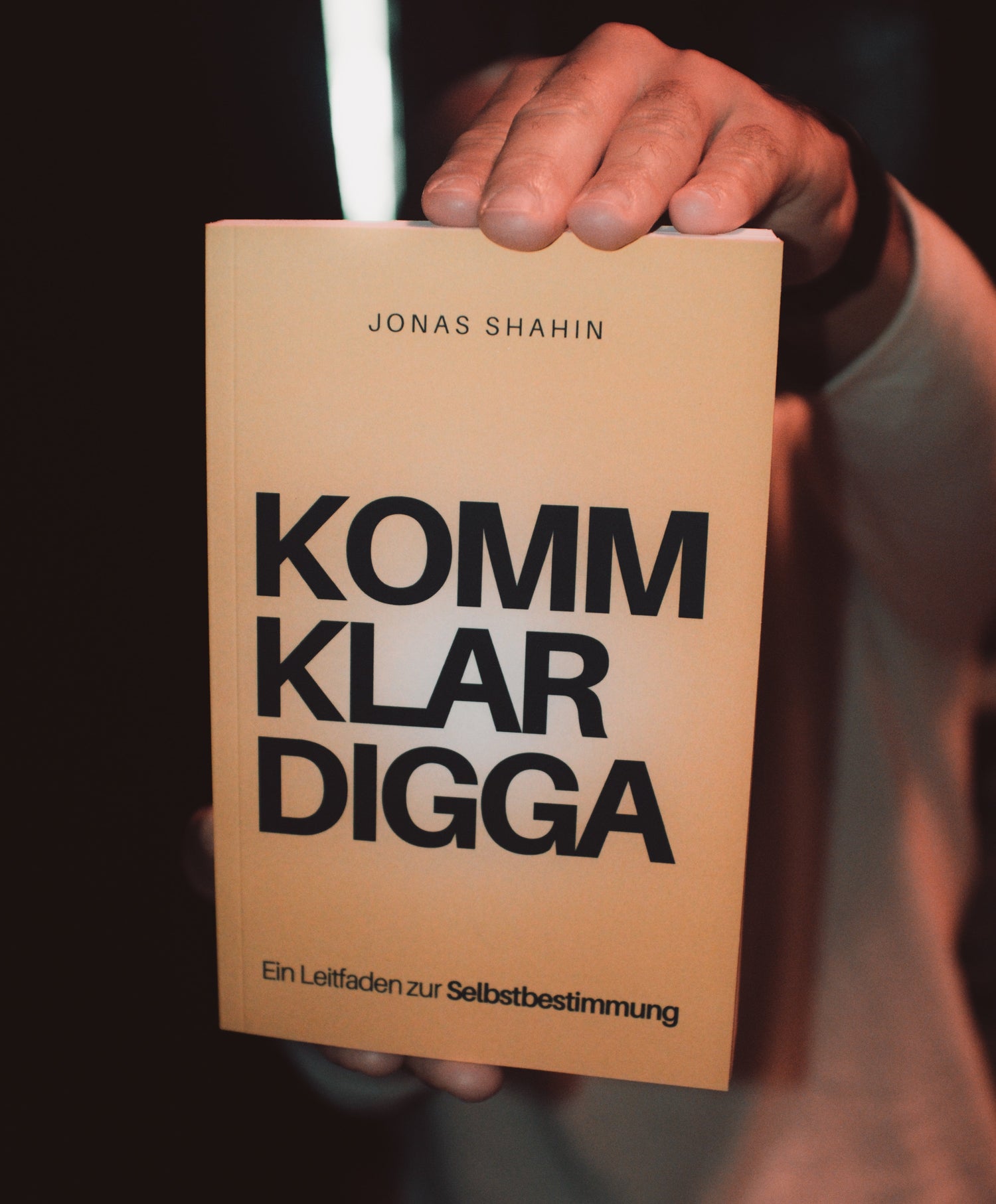 Jonas Shahin hält sein Buch KOMM KLAR DIGGA – Ein Leitfaden zur Selbstbestimmung in der Hand.