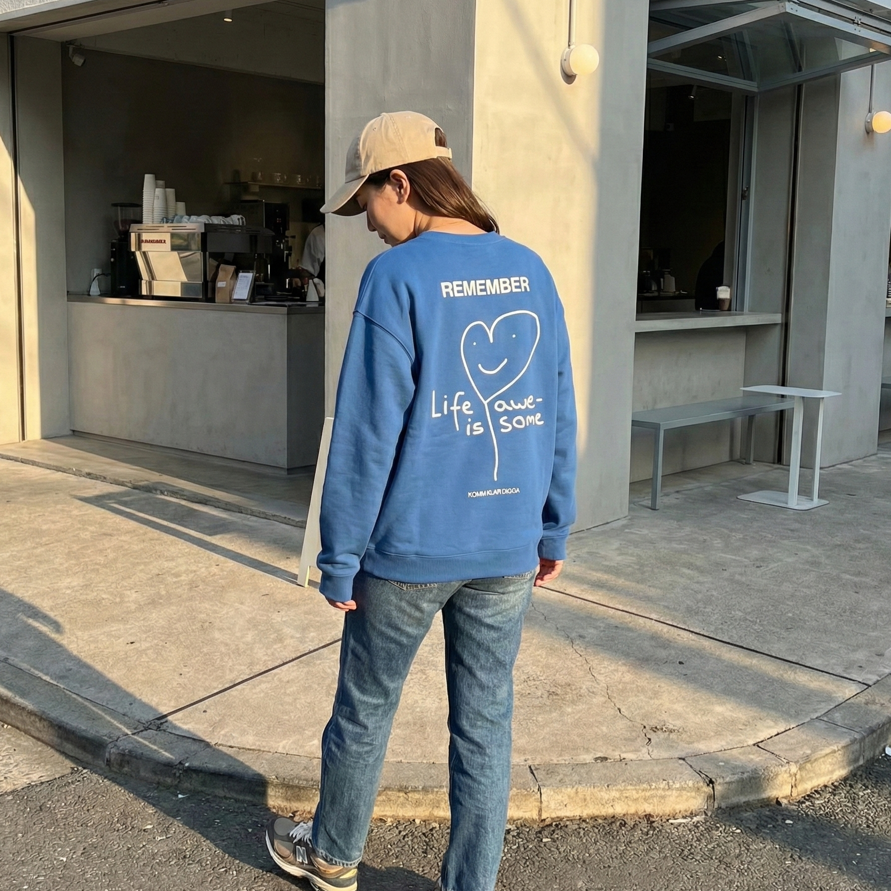 Blaues Unisex Sweatshirt von KOMM KLAR DIGGA mit Rückenprint „Life Is Awesome“, minimalistisches Herz-Design, lässiger Streetwear-Look im Alltag getragen.