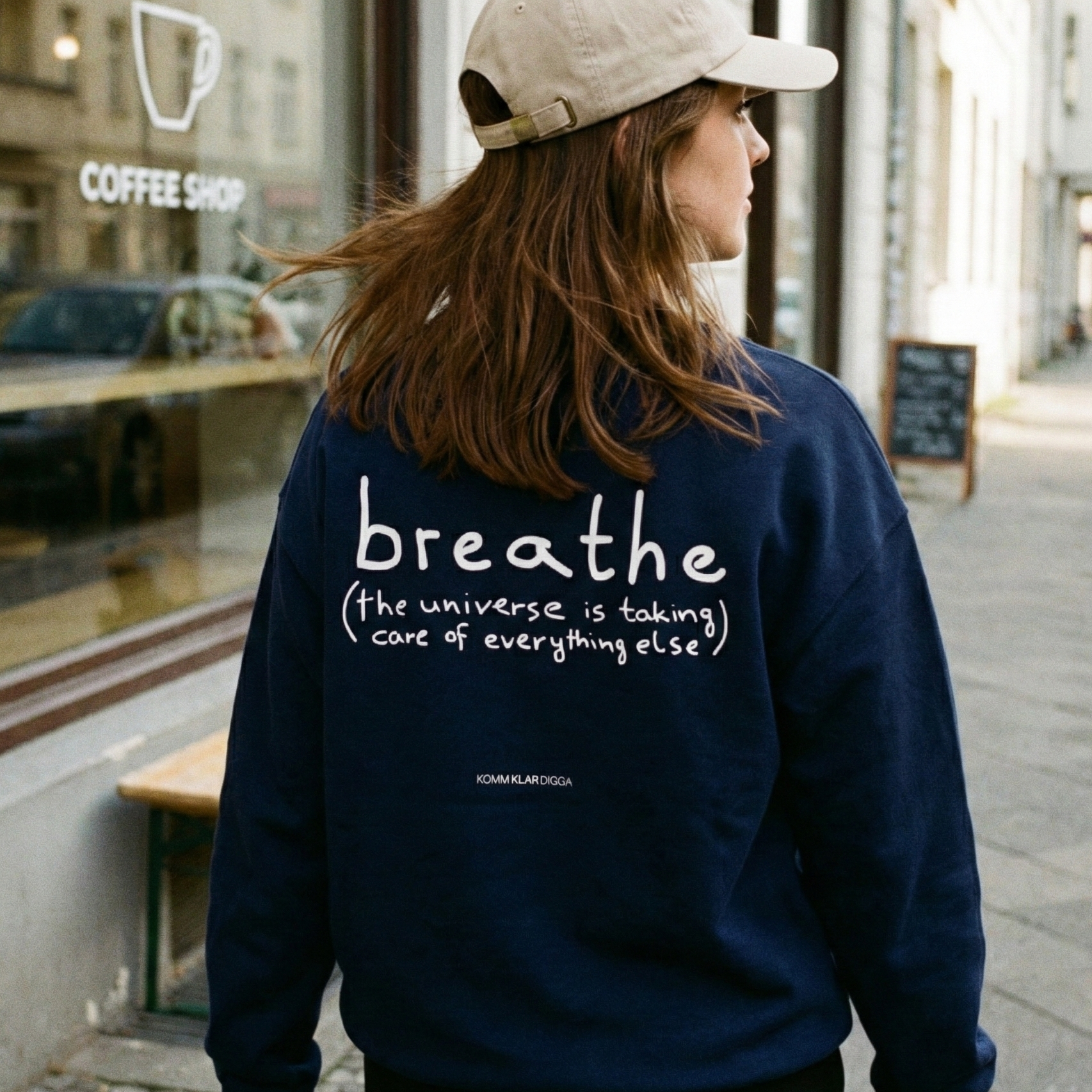 Dunkelblaues Heavy Unisex Sweatshirt aus 100 % Bio-Baumwolle von KOMM KLAR DIGGA mit Rückenprint „breathe (the universe is taking care of everything else)“, authentischer Streetwear-Look im urbanen Alltag.
